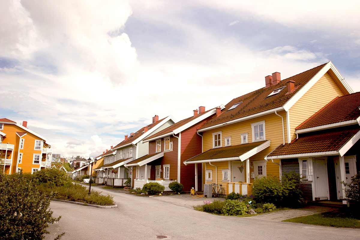 Flere hus i gul, grå og rød farge i en gate, til illustrasjon for skifte kledning og tak