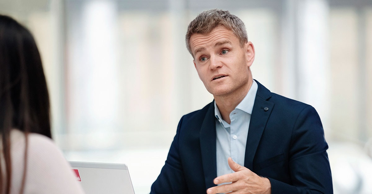 Anders jobber som boliglånsrådgiver i BN Bank og snakker med kunde, til illustrasjon for eiendomsmegler Krogsveen
