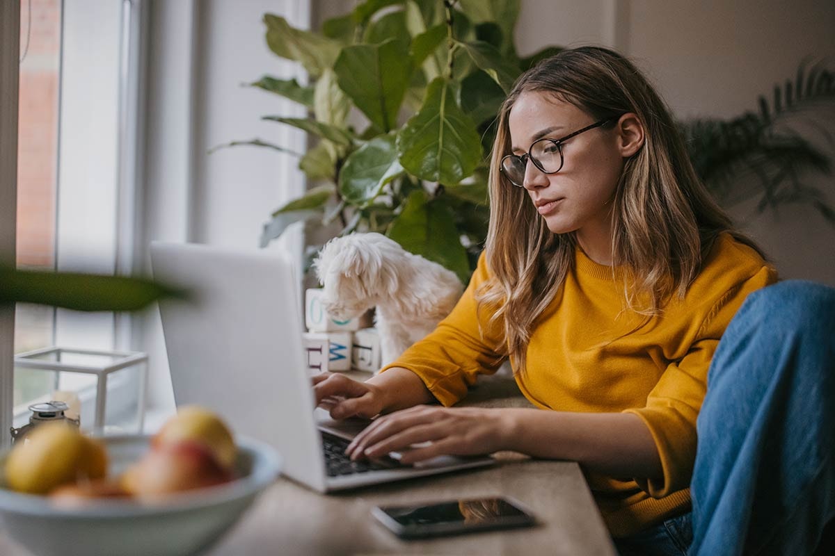 Kvinne sitter med laptop og jobber, til illustrasjon for å unngå skattesmell