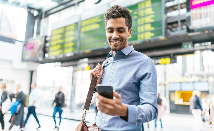 Mann på flyplass ser på mobiltelefonen, illustrasjon til mobilbank bedrift