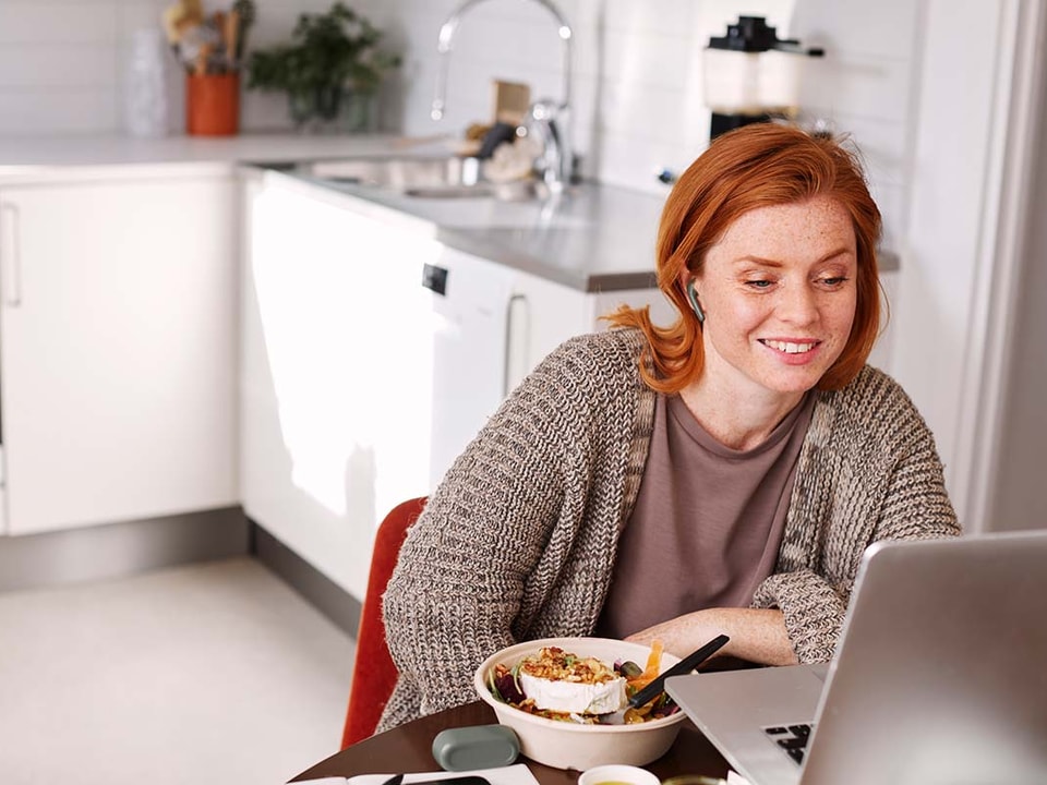 Dame ser på pc ved kjøkkenbordet, til illustrasjon for spareplan