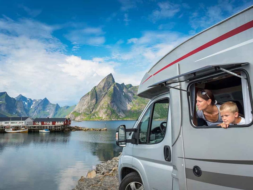 Dame og gutt i en caravan i lofoten med fjell i bakgrunnen, til illustrasjon caravanlån
