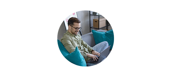 Mann sitter i sofa og jobber på PC, til illustrasjon for sette opp budsjett